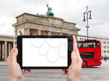 travel concept - tourist photograph tourist double decker bus near Brandenburg gate in Berlin, Germany on tablet pc with cut out screen with blank place for advertising logo