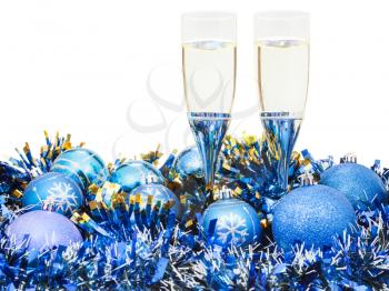 two glasses of sparkling wine at blue Christmas balls and tinsel isolated on white background