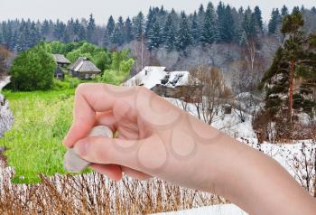 season concept - hand deletes winter village by rubber eraser from image and summer country landscape are appearing