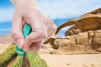weather concept - hand deletes sand in desert by rubber eraser from image and green grass and country road are appearing