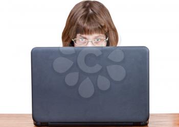 girl with spectacles looks over cover of open laptop