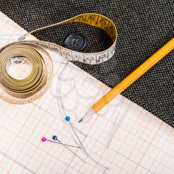 dressmaking still life - above view of cutting table with pattern, measuring tape, pencil, pins, tweed coat