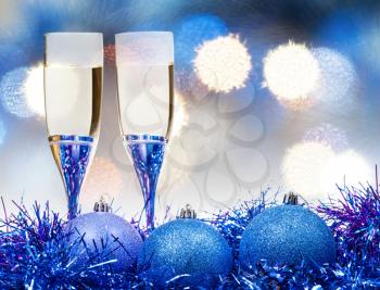 Christmas still life - two glasses of champagne at blue Xmas decorations with duffuse blue Christmas lights bokeh background