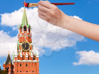 travel concept - hand with paintbrush paints the red star on Spasskaya tower on Moscow Kremlin