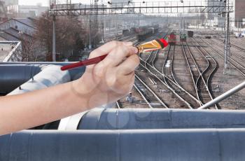 travel concept - hand with paintbrush paints red locomotive on railway station