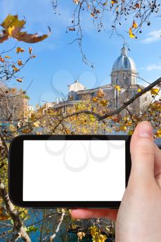 travel concept - hand holds smartphone with cut out screen and autumn Rome city on background