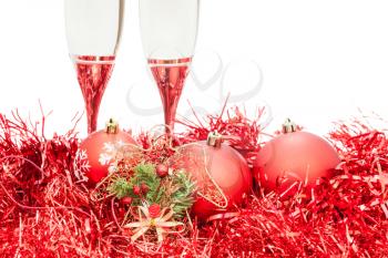 two glasses of champagne and angel figure at red Christmas decorations isolated on white background