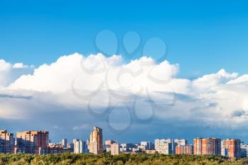 large low white cloud in blue sky over residential district in summer day