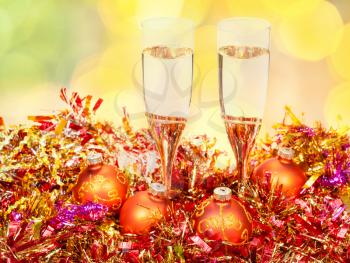 Christmas still life - two glasses of champagne at golden Xmas decorations with yellow and green blurred Christmas lights bokeh background