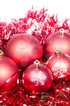 five red Christmas baubles and tinsel isolated on white background