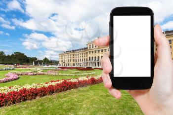 travel concept - tourist photographs of garden in Schloss Schonbrunn palace in Vienna on smatphone with cut out screen with blank place for advertising logo
