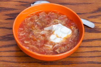 cabbage soup in meat broth with sour cream in ceramic bowl on wooden table