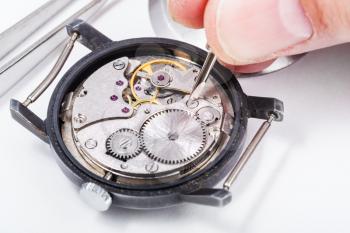 adjusting old mechanic wristwatch - horologist repairs old watch close up