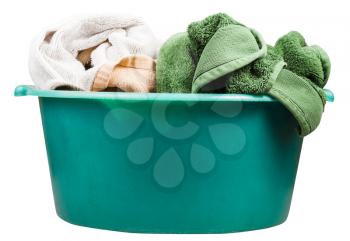 side view of round green plastic wash basin with towels isolated on white background