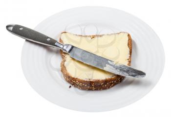 grain bread and butter sandwich with table knife on white plate isolated on white background