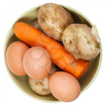 above view of boiled eggs, carrot and potatoes in a ceramic bowl isolated on white background