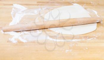 rolling pin and rolled dough on wooden table
