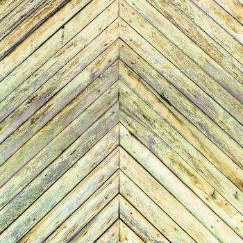 herringbone pattern background from shabby green painted planks on wall of old wooden house