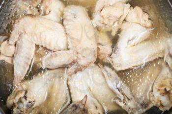 many boiled chicken wings in greasy chicken bouillon in stewpan