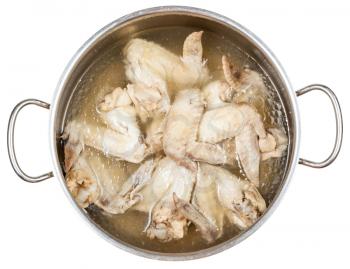 stewpan with boiled chicken wings in greasy chicken bouillon isolated on white background