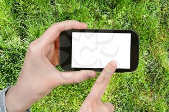 gardening concept - farmer photographs green grass of lawn on smartphone with cut out screen with blank place for advertising