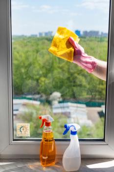 washing home window in spring - washer cleans window glass by rag in sunny day