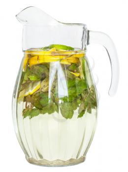 side view of glass pitcher with natural lemonade drink from lemon, lime, mint isolated on white background
