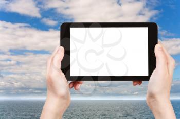 travel concept - tourist photographs North Sea in morning on tablet pc with cut out screen with blank place for advertising