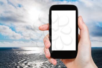 travel concept - tourist photographs North Sea in evening on smartphone with cut out screen with blank place for advertising