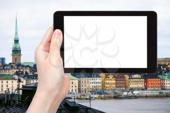 travel concept - tourist photographs waterfront of Gamla stan (Old Town) in Stockholm, Sweden on tablet pc with cut out screen with blank place for advertising