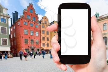 travel concept - tourist photographs historical houses on Stortorget square in Stockholm, Sweden on smartphone with cut out screen with blank place for advertising