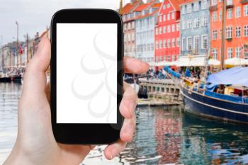 travel concept - tourist photographs Nyhavn (New Harbour) in Copenhagen, Denmark on smartphone with cut out screen with blank place for advertising