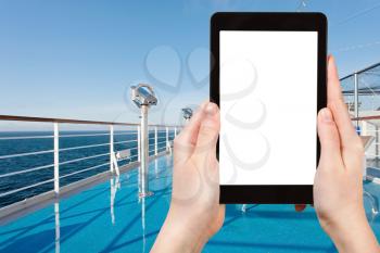 travel concept - tourist photographs ocean from desk of cruise liner on tablet pc with cut out screen with blank place for advertising