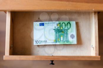 above view of stack of one hundred euro banknotes in drawer of nightstand