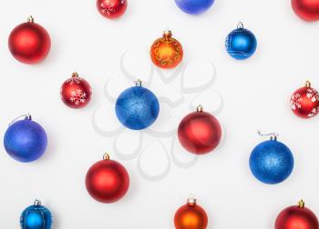 various blue, red, orange christmas balls arranged on white background
