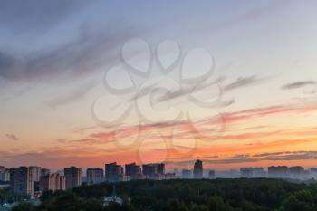 blue sky with orange sunlight over city at summer dawn