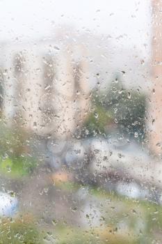 rainy weather in city - view of wet window glass of apartment house