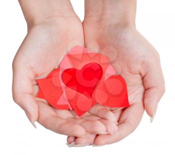 one red heart above pile of paper hearts on female palms isolated on white background