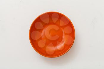 top view of orange bowl on white plastering plate