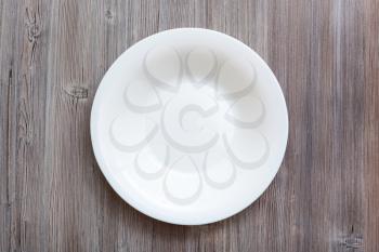 above view of one white deep plate on gray brown table
