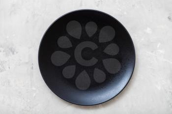 above view of one black plate on gray concrete surface