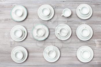 food concept - top view lot of white cups and saucers on gray brown board