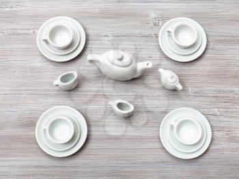 food concept - top view of cups with saucers and tea set on gray brown table