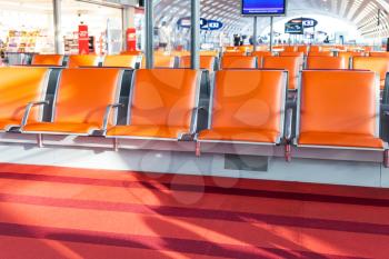 empty orange seat in departure hall of airport