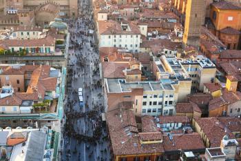 travel to Italy - above view of street with crowd of people and houses in Bologna city from Torre Asinelli ( Asinelli Tower) in evening