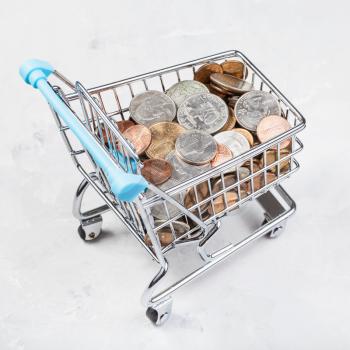 shopping trolley with US coins on concrete board