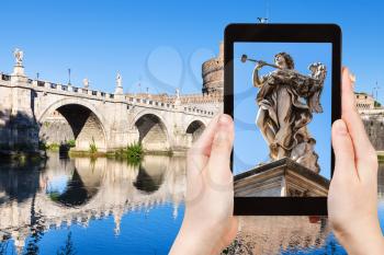 travel concept - tourist photographs Angel statue on bridge in Rome city on tablet in Italy