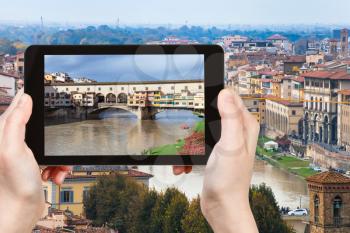 travel concept - tourist photographs Ponte Vecchio in Florence city on tablet in Italy