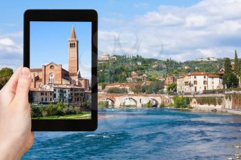 travel concept - tourist photographs Sant Anastasia Church and Ponte Pietra bridge in Verona city on tablet in Italy