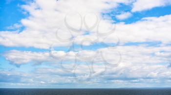 white clouds in blue sky over calm Baltic Sea in autumn day